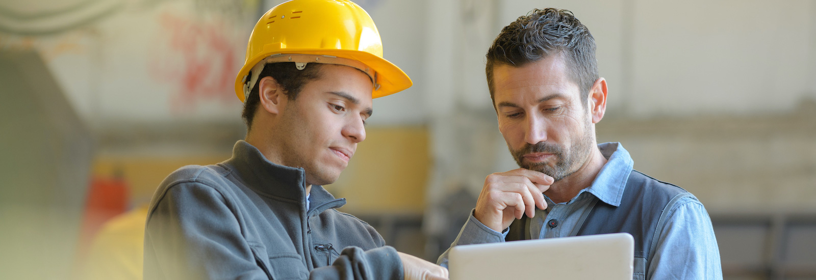 two male electrical power workers looking at computer