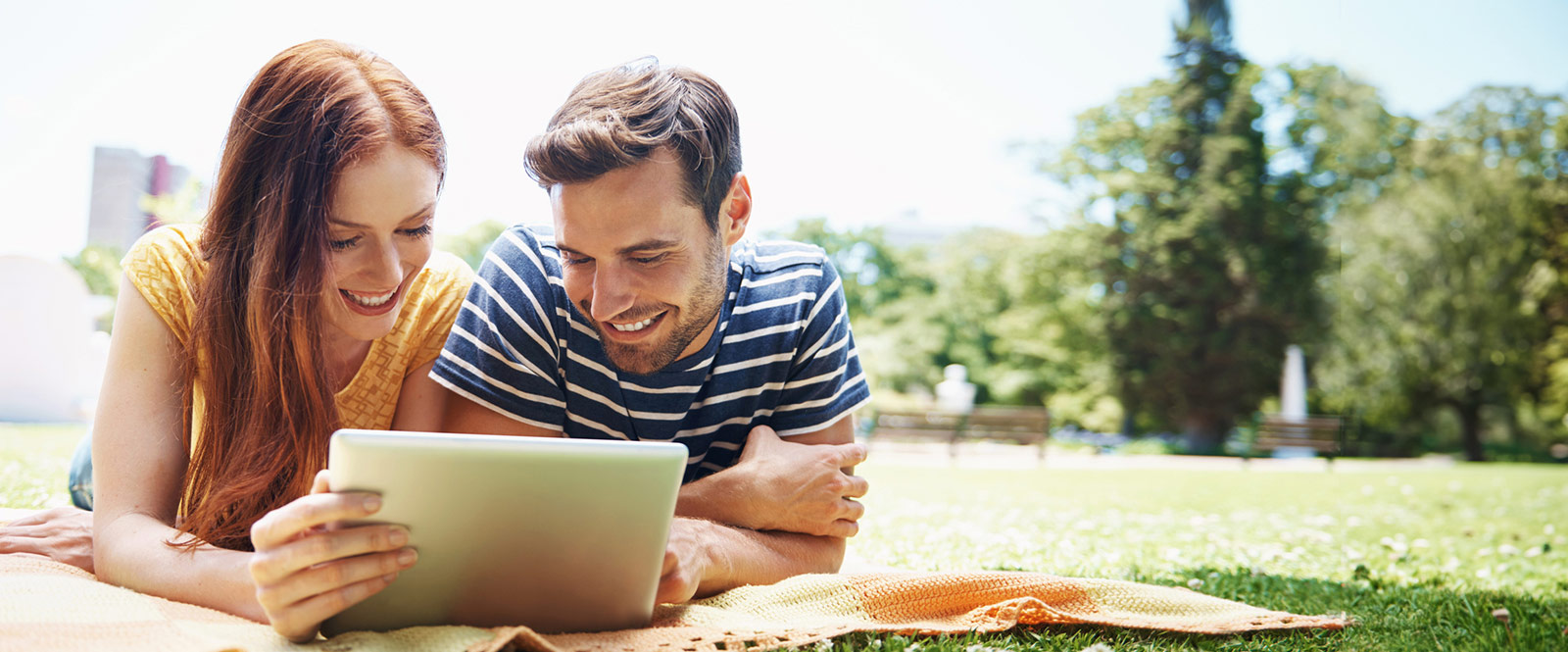 Couple on a blanket using a tablet.